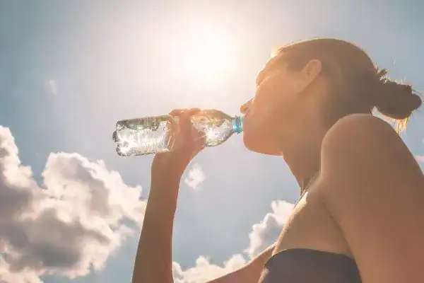 Hydration: The Secret Ingredient for a Toned Stomach and Enhanced Fitness 3 Image of woman drinking water to hydrate Harrow after run.